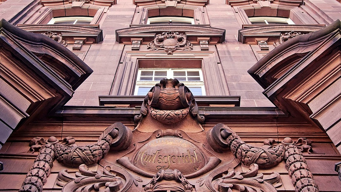 Hausfassaded des Amtsgerichts Mannheim aus rötlichem Stein mit Ornamenten und Verzierungen.