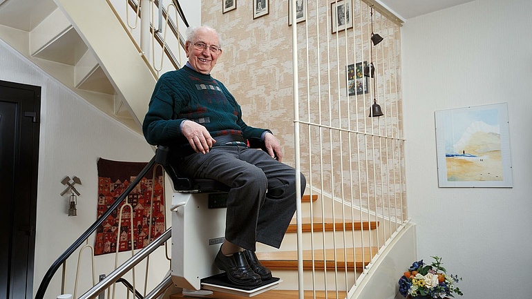 Ein älterer Herr benutzt einen Treppenlift.