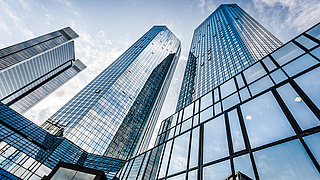 Blick von unten auf verspiegelte Hochhäuser.