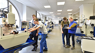 Azubis bei der praktischen Prüfung in einer Werkshalle