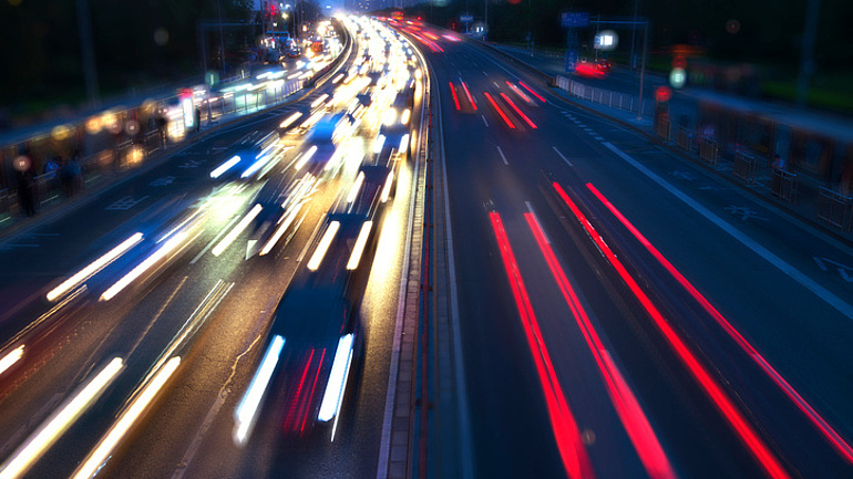 Blick bei Dunkelheit auf eine mehrspurige Autobahn: Die Lichter der Fahrzeuge erscheinen verschwommen.