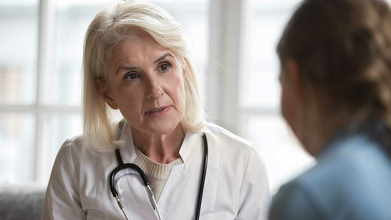 Eine Ärztin im mittleren Alter spricht mit einer Patientin.