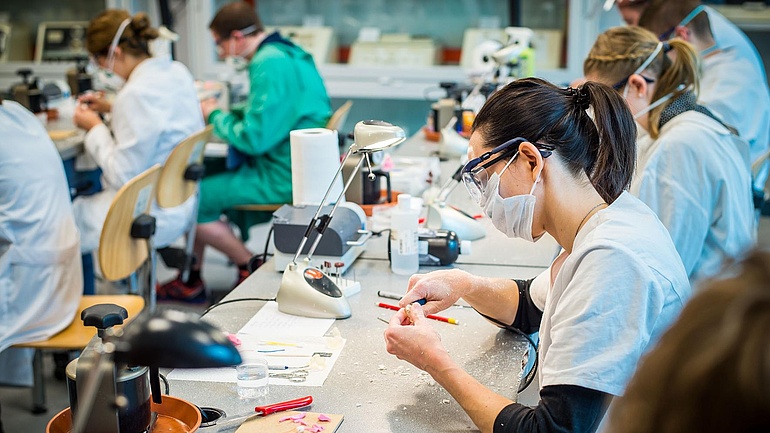 In einer Hörakustiker-Werkstatt arbeiten zahlreiche Mitarbeiter an der Produktion von Hörgeräten.