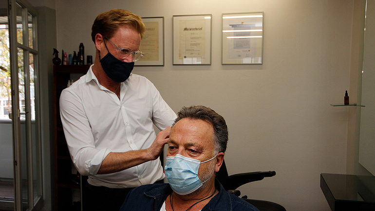 Marco Illiges steht hinter einem Kunden, beide tragen eine Gesichtsmaske.