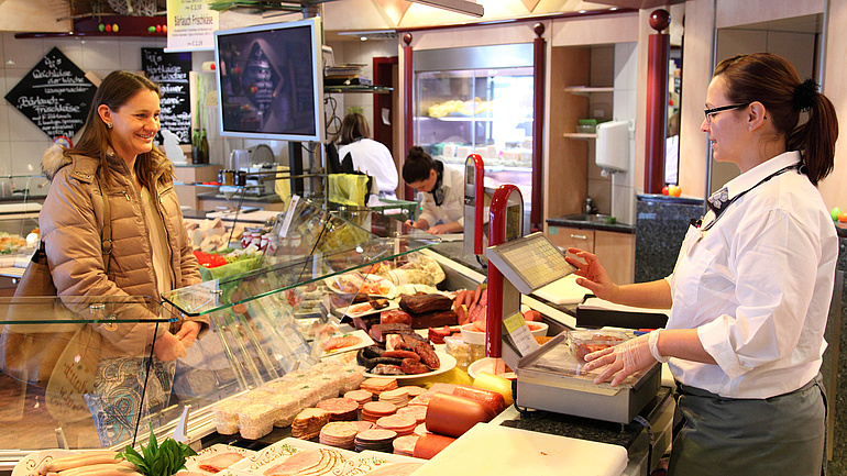 Fachverkäuferin Lebensmittelhandwerk bedient Kunden an der Theke