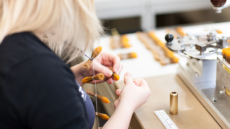 Bürsten- und Pinselmachermeisterin formt Pinselhaare und bündelt diese.