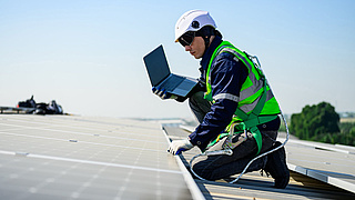 Mann auf Dach installiert Photovoltaikanlage