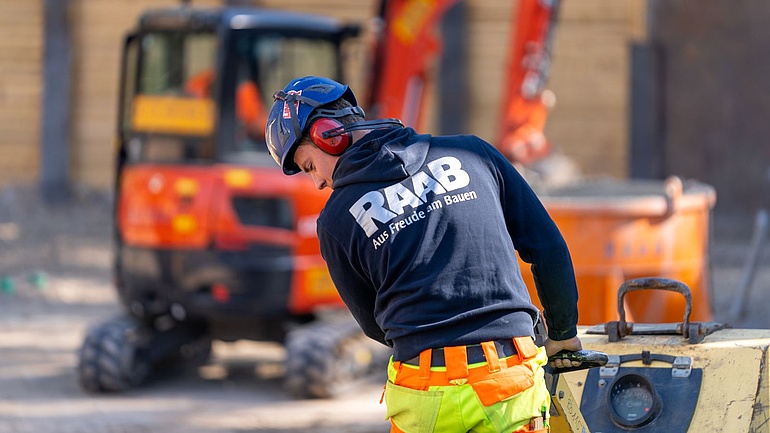Ein Mitarbeiter planiert eine Straße.
