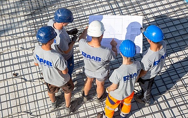 Azubis der unterschiedlichen Gewerke gehen den Bauplan durch.