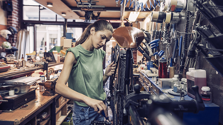 Fahrradreparateurin repariert ein Fahrrad im Laden.