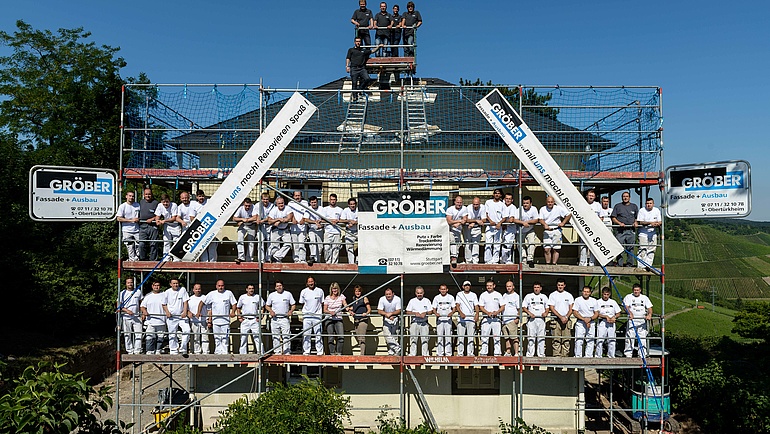 Das Team der Christian Gröber GmbH mit etwa 60 Mitarbeitern steht zusammen auf einem Gerüst.