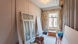 Altbauwohung bei Sanierungsarbeiten: Ein neues Fenster sowie Dämmplatten stehen für die Renovierung breit.