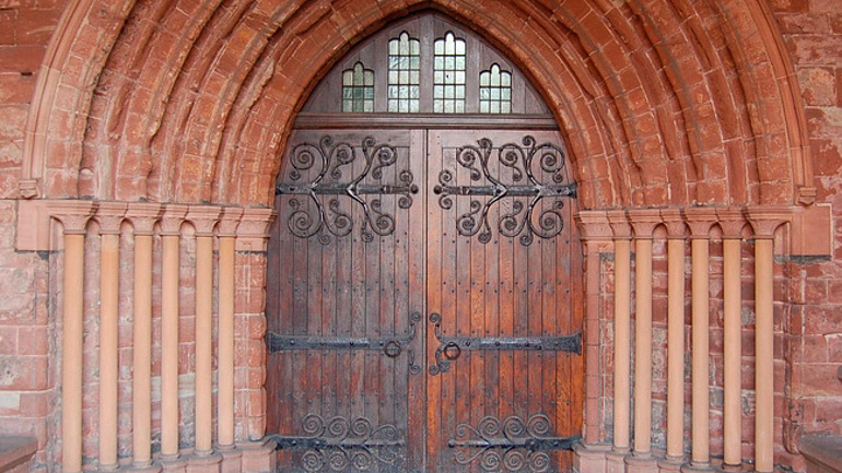 Historische Kirchentür Eisengriffen in einem Sandsteinbogen.