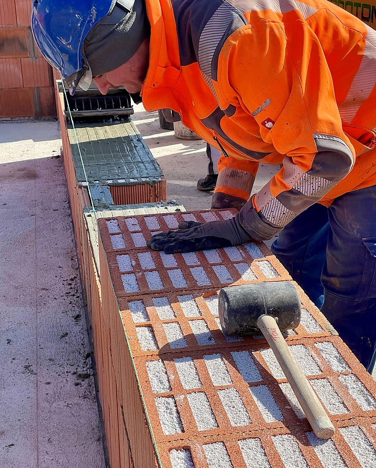 Ein Maurer setzt eine Wand.