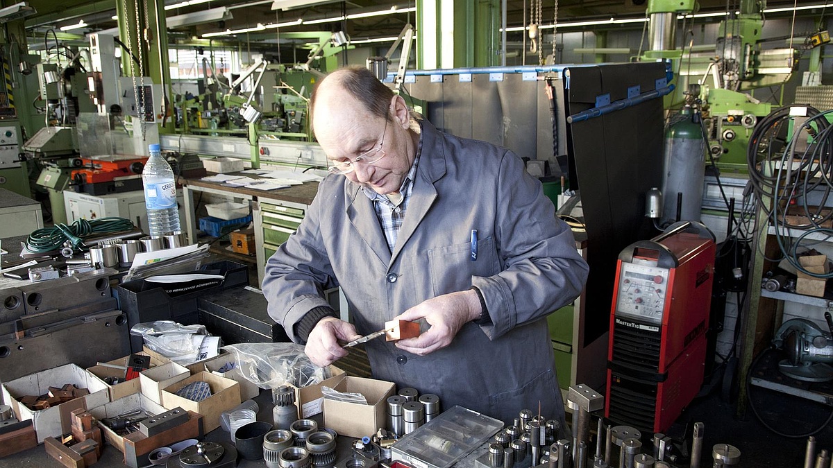 Älterer Handwerker bearbeitet ein Metallstück.