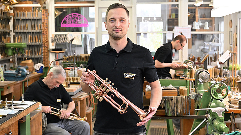 Max Hertlein mit einer Kupfer Trompete in der Hand. 