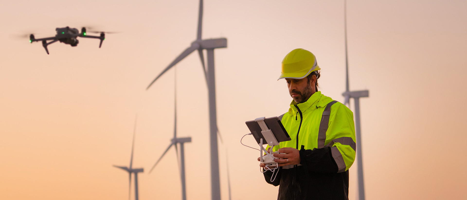 Ingenieure lassen Drohnen fliegen und vermessen und überprüfen Windkraftanlagen während eines Sonnenuntergangs.