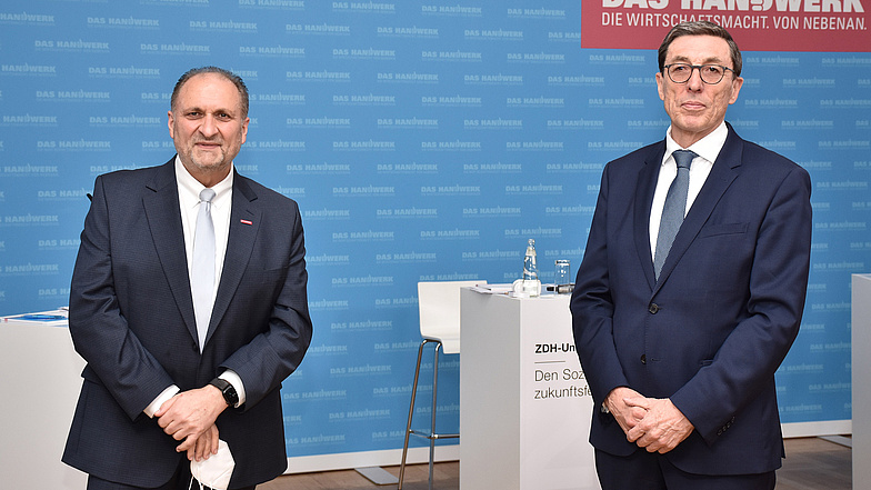 ZDH-Präsident Hans Peter Wollseifer und Prof. Dr. Rainer Schlegel, Präsident des Bundessozialgerichts vor blauer Handwerksfotowand