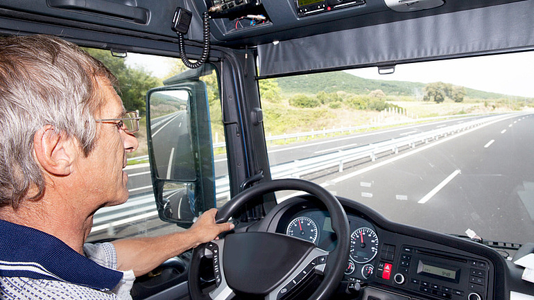 Seitenblick auf einen LKW-Fahrer in der Fahrerkabine.