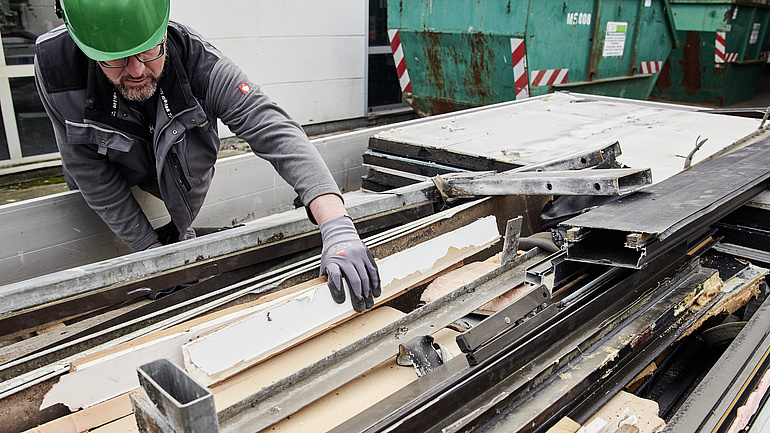 Mitarbeiter sortiert Aluminium im Container