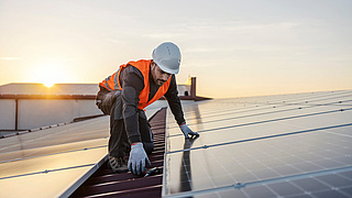 Dachdecker checkt Photovoltaikanlage auf dem Dach