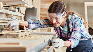 Junge Tischlerin schleift Holz.