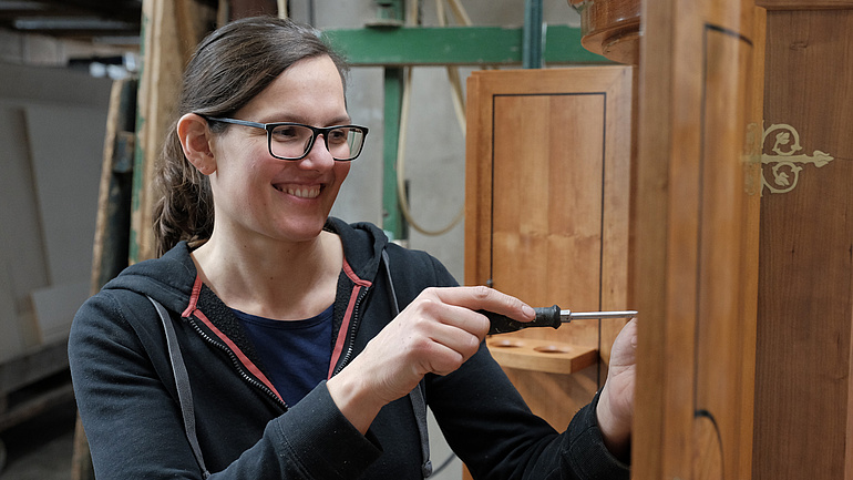 Handwerkerin Johanna Röh schraubt etwas an einem Schrank fest.