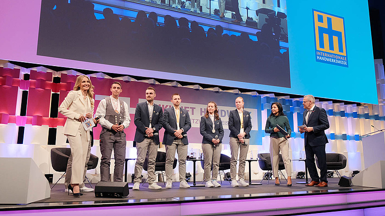 Bundeswirtschaftsministerin Katherina Reiche und ZDH-Präsident Jörg Dittrich mit deutschen Medaillengewinnerinnen und -gewinnern der EuroSkills 2025 bei der Eröffnung der ZUKUNFT HANDWERK und der IHM 2026 in München.