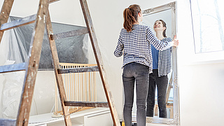 Junge Frau hängt Spiegel an die Wand