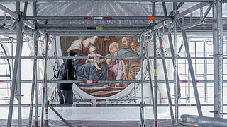 Historischenes Gemälde vor dem ein Metallgerüst aufgebaut ist.